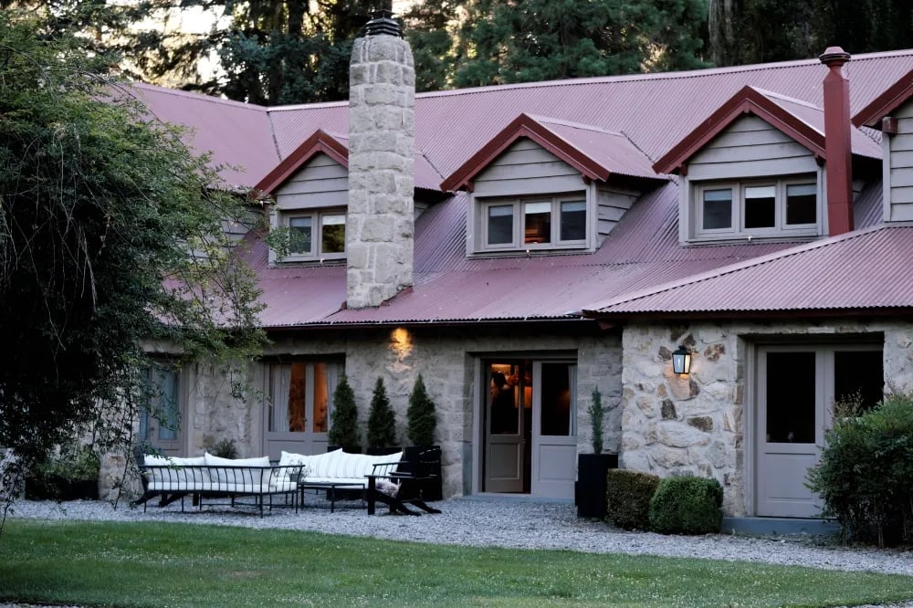 Stone and wood lodge exterior with a red roof and outdoor seating area
