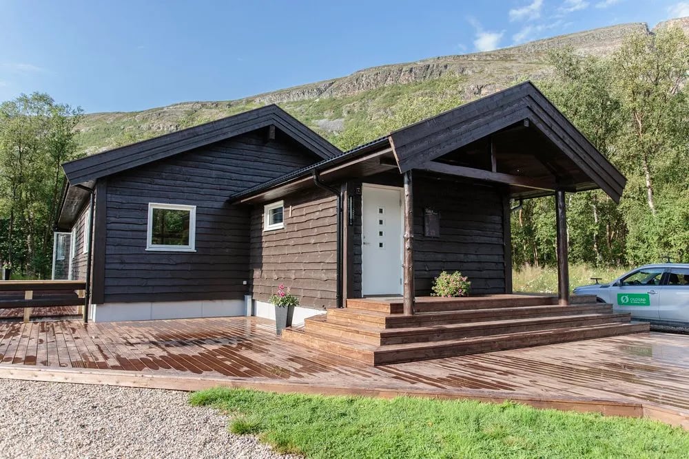 Modern dark wood lodge exterior with a covered entrance and large windows.