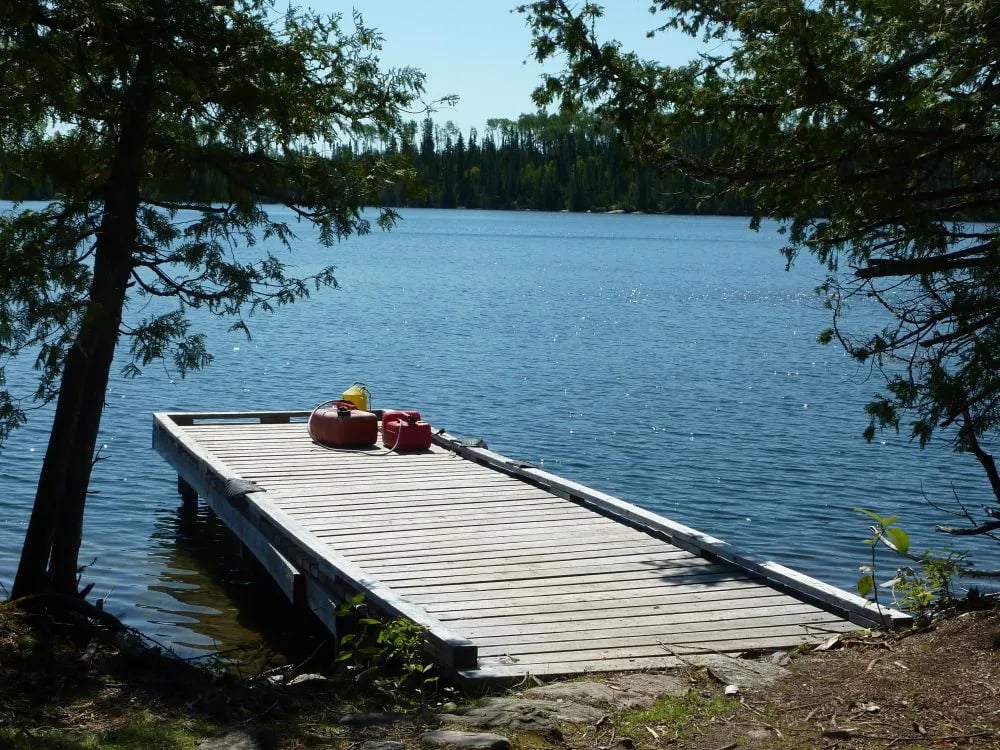 Long wooden dock extending into a calm lake on a sunny day