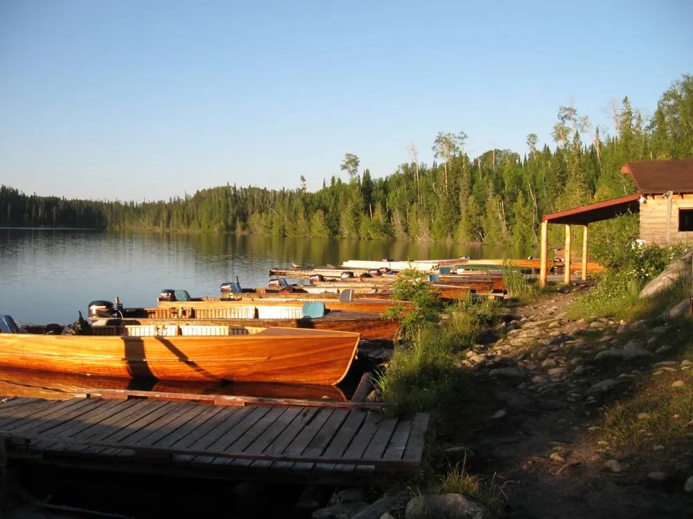 Fleet of wooden cedar strip boats lined up at a dock on a lake