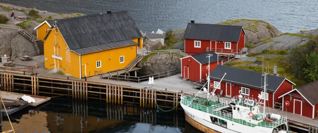 Nusfjord harbor with yellow and red cabins and a fishing boat