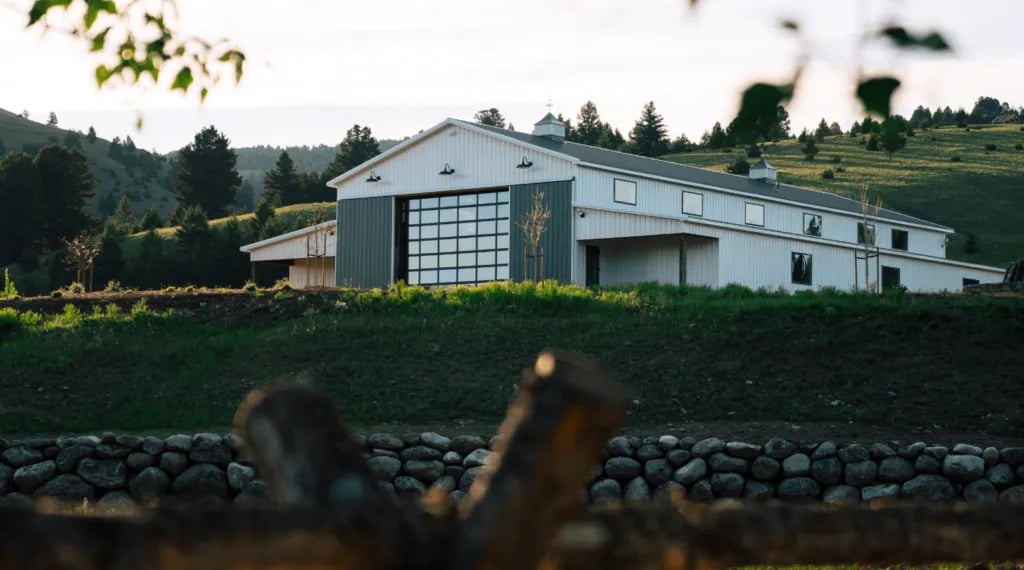 a large white barn on a hillside