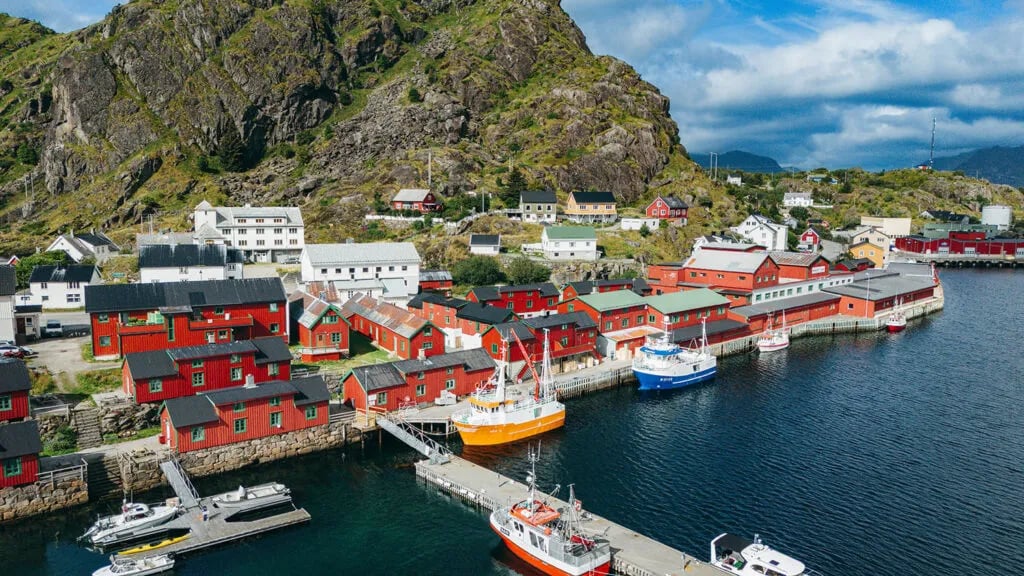 Aerial view of a fishing village with red rorbuer and boats docked along the shore