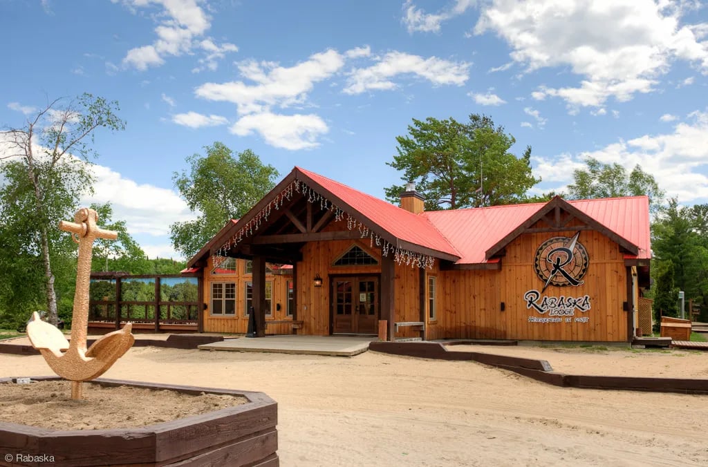 Main lodge building exterior with a red roof, wooden facade, and a large anchor decoration.