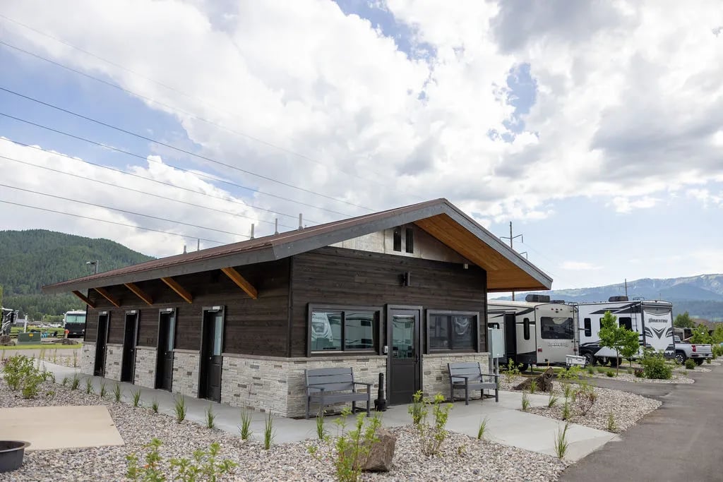 Modern communal bathhouse building with stone and wood siding under a cloudy sky