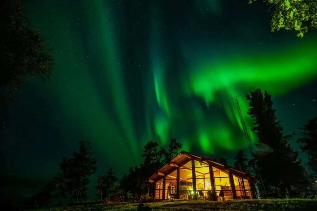 Lodge building illuminated under vibrant green Northern Lights