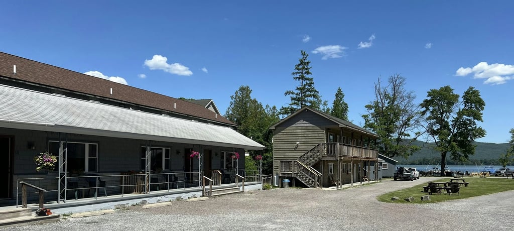 Two-story Deluxe Suite building with wooden balconies and a gravel parking area