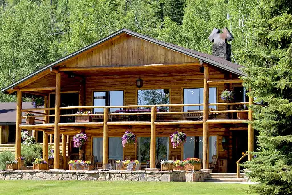 Rustic wooden main lodge with a wrap-around porch and hanging flower baskets.