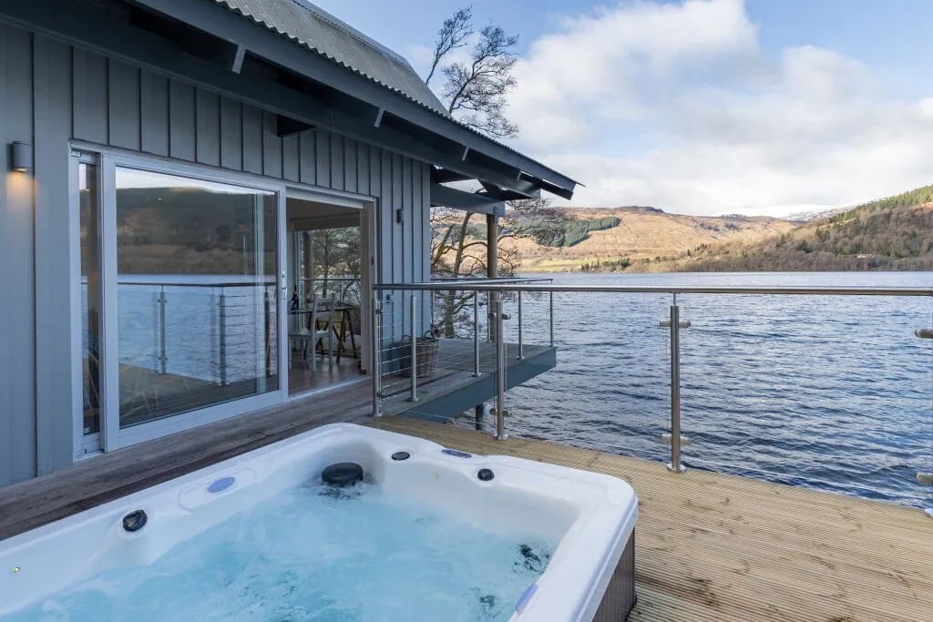 Osprey Lodge hot tub on a deck with a wide view of a lake and hills.