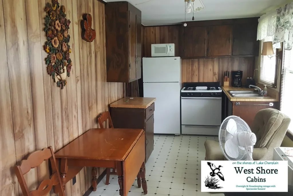 Cabin 3 kitchen and dining area with wood-paneled walls, a white refrigerator, and a wooden table