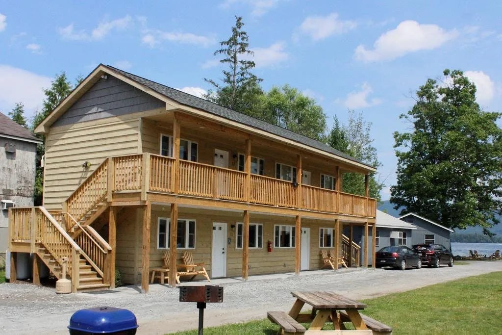 Duplex cottages and parking area nestled among trees on a sunny day