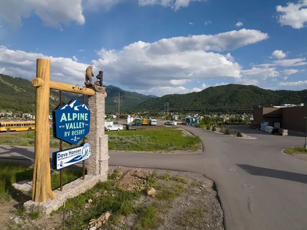 Wooden and stone entrance sign for Alpine Valley RV Resort with bear statues on top