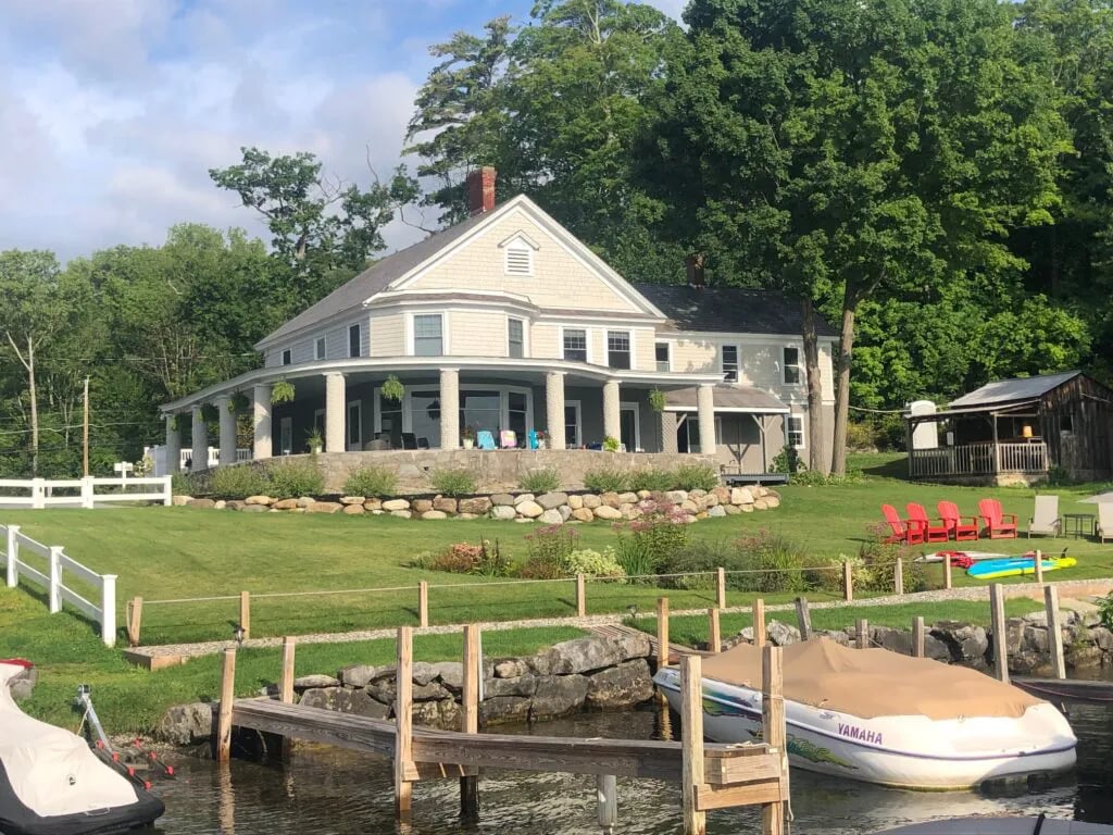Lodge building with a curved porch, cornhole boards on a green lawn