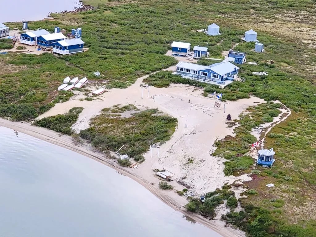 Bird's eye view of Peterson's Point Lake Lodge complex with multiple blue buildings and small cabins by the lake.