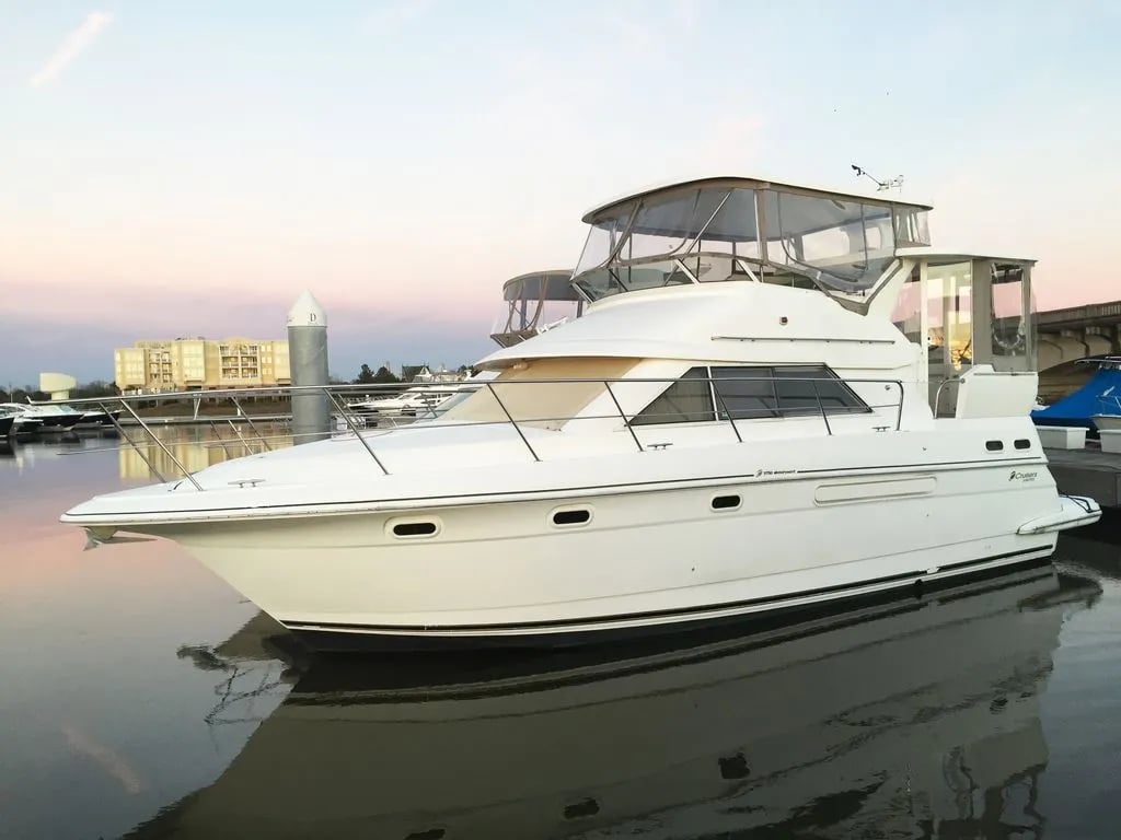 White yacht docked at sunset with city buildings in the background