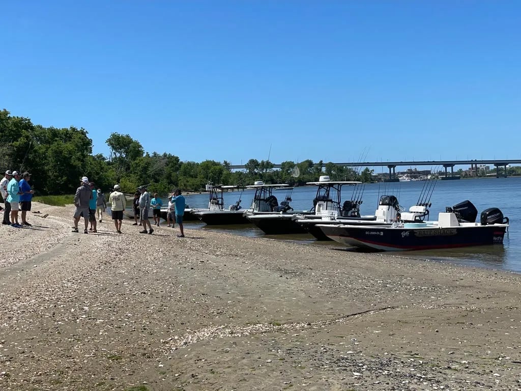 Several fishing boats beached on a sandy shore with a group of people walking