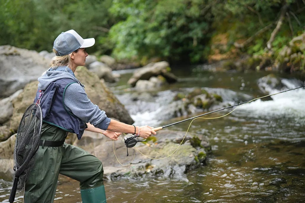 young woman fly fishing in a mountain river