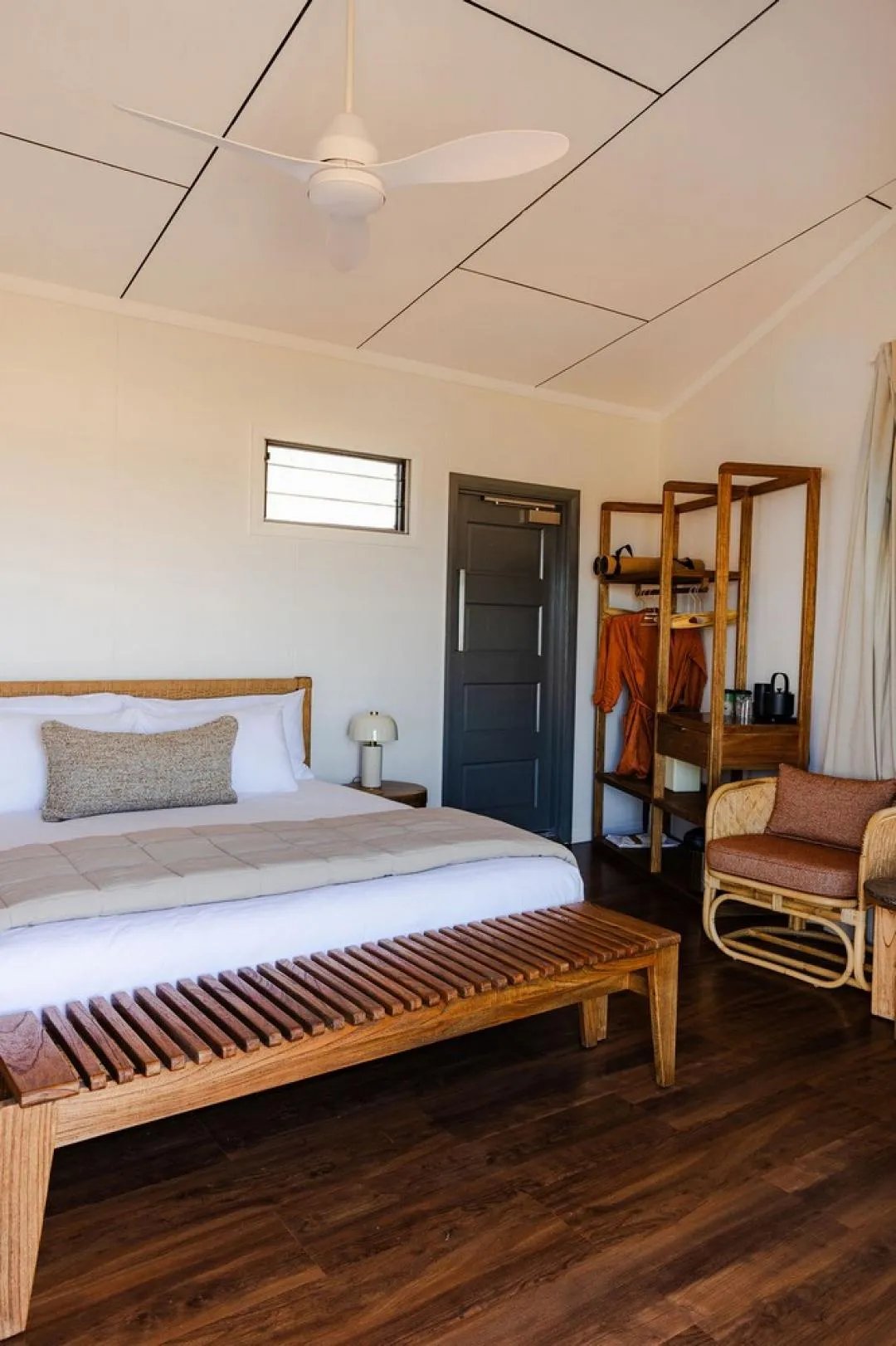 Bedroom with a king bed, ceiling fan, and a wooden shelving unit with robes