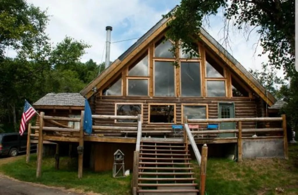 Front exterior of the main log lodge building with large windows and a wooden deck.
