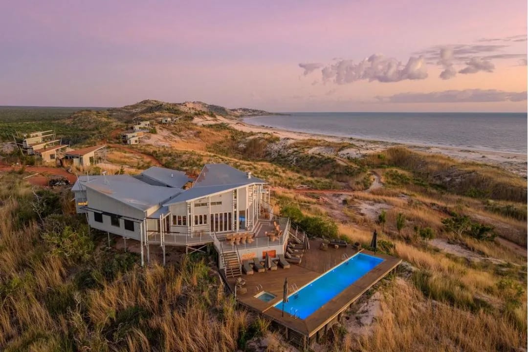 Aerial view of the main lodge building and pool on a hill overlooking the coastline