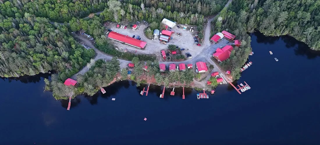 Aerial view of the Bryson Lake Lodge compound with red-roofed buildings and docks on the waterfront