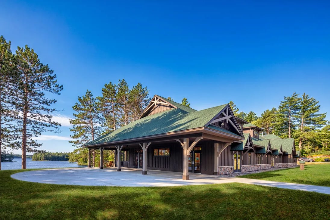 Lodge building with a green roof nestled among vibrant autumn trees along a paved road