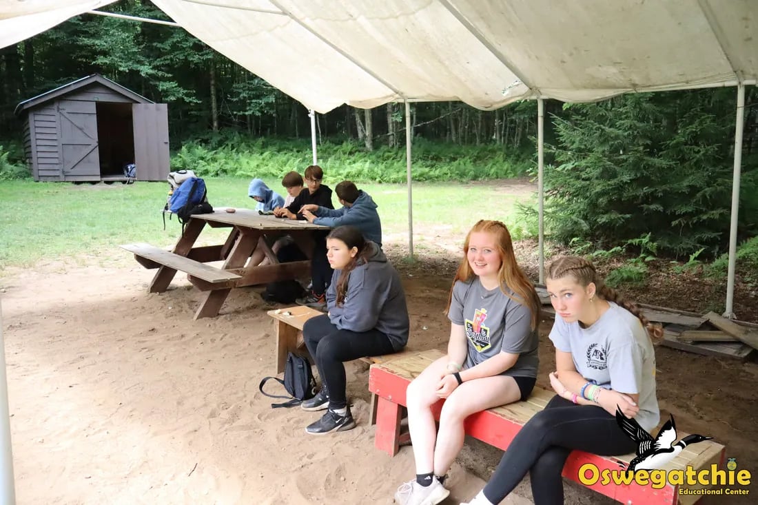 Speaker addressing a large group of campers seated in an outdoor amphitheater.