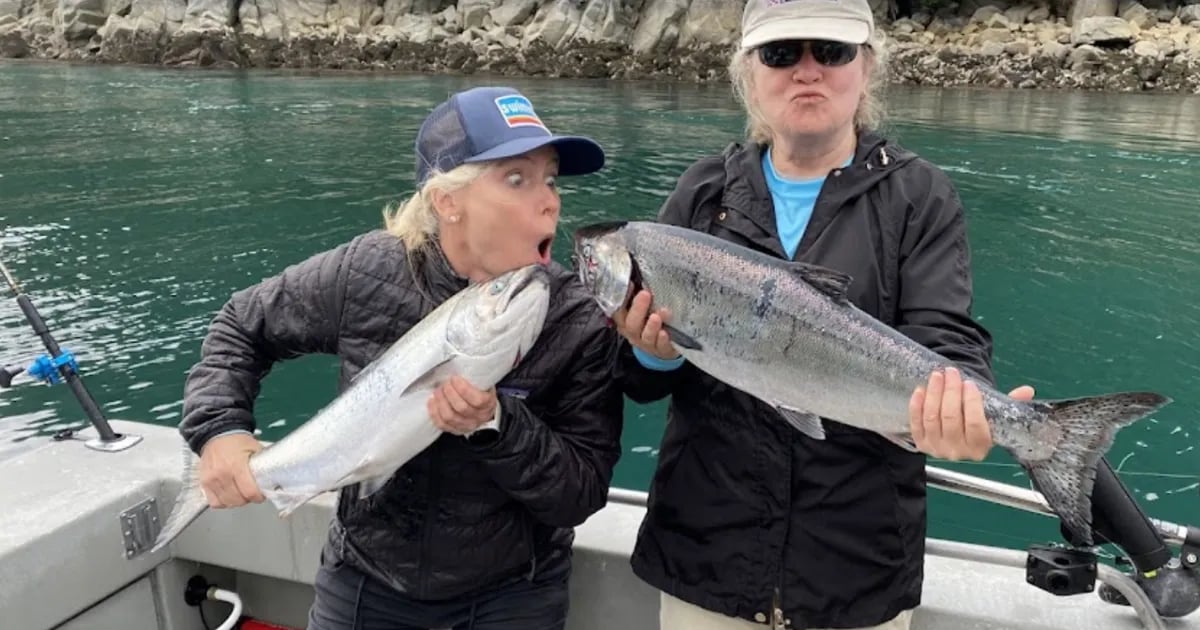 Four anglers on a boat proudly holding their salmon catches