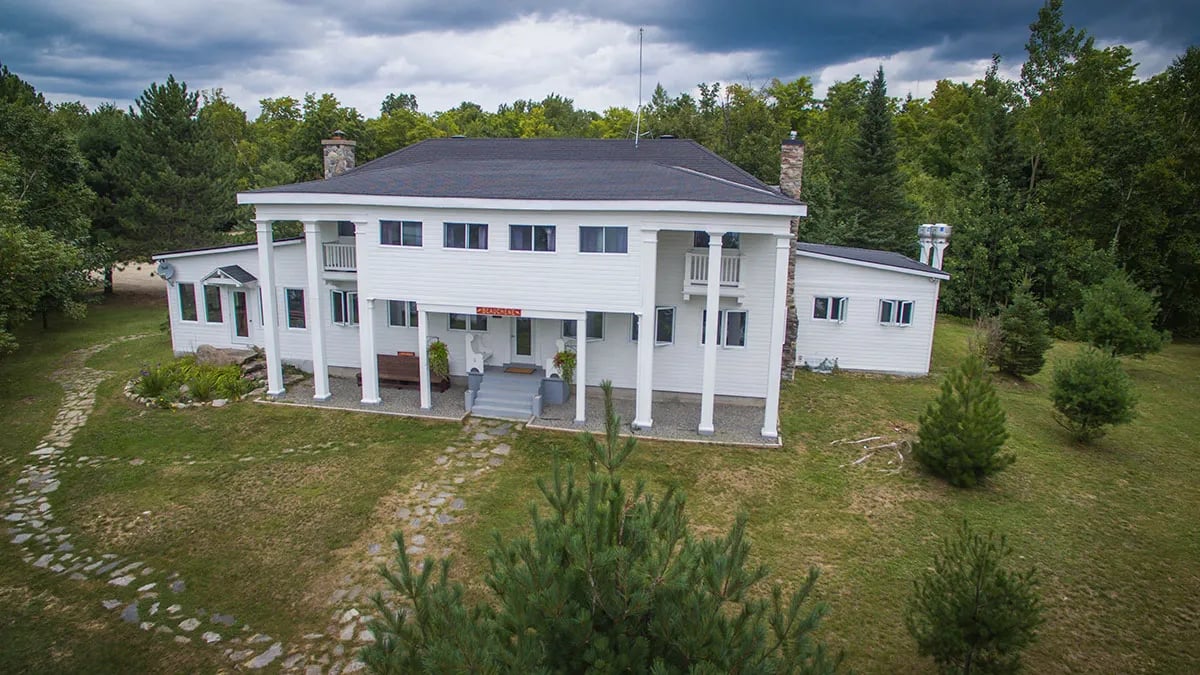 Front view of the white main lodge with columns and a green lawn