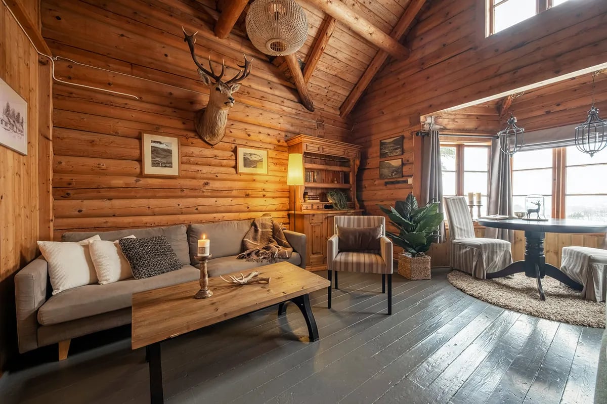 Cozy common lounge area with a large stone fireplace, wooden walls, and comfortable armchairs.
