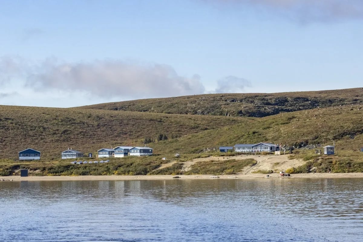 Peterson's Point Lake Lodge buildings nestled along the lake shore with rolling tundra hills in the background.
