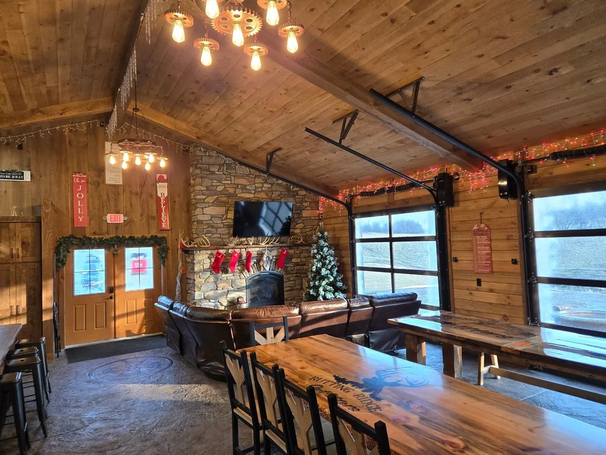 Spacious lodge common area with a stone fireplace, long wooden dining table, and large windows