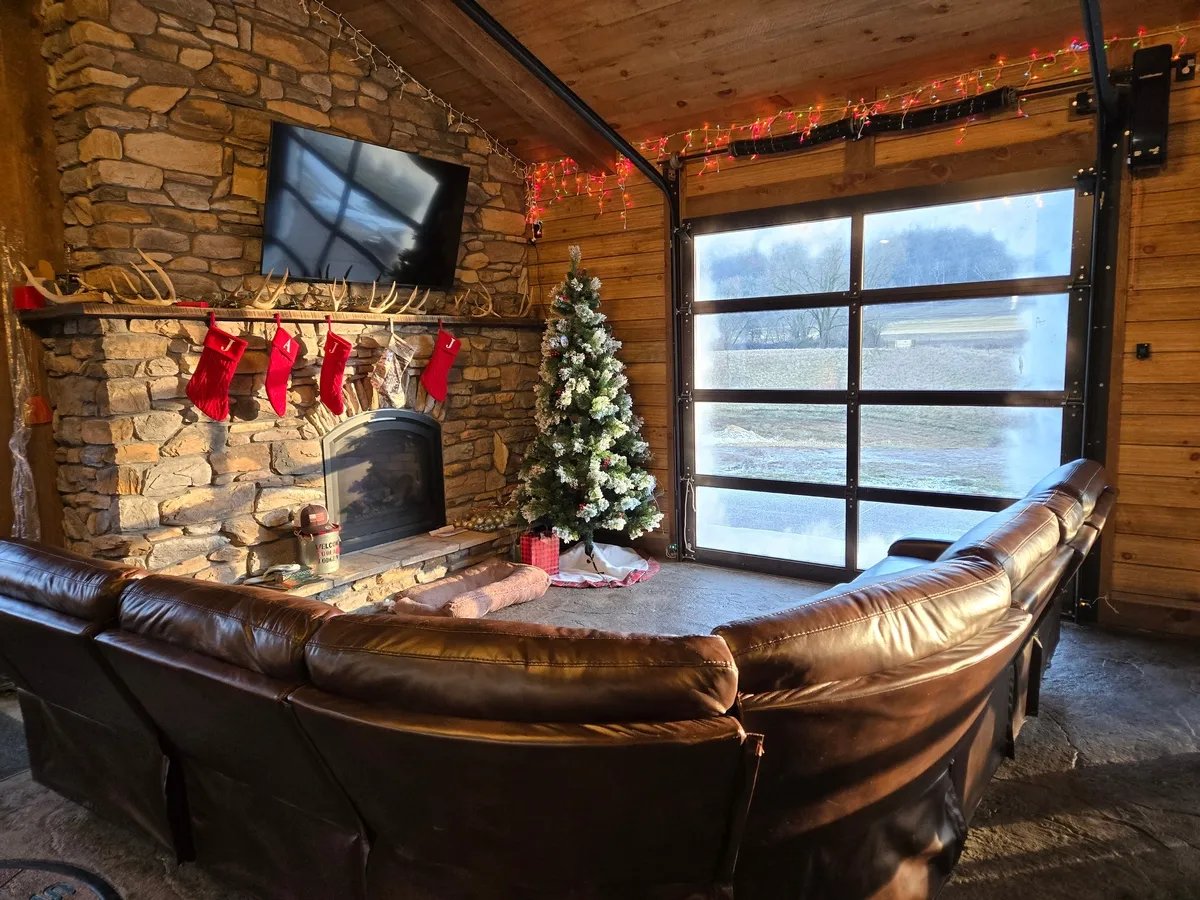 Cozy lodge living area with a brown leather sofa, stone fireplace, and Christmas tree
