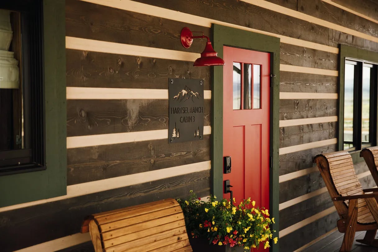 Close-up of a cabin exterior with a red door, log siding, and a red light fixture.