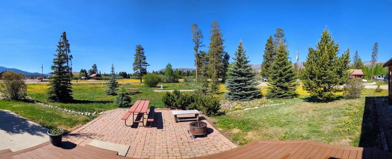 Panoramic view of The Trailboss cabin's deck and surrounding green field with distant trees