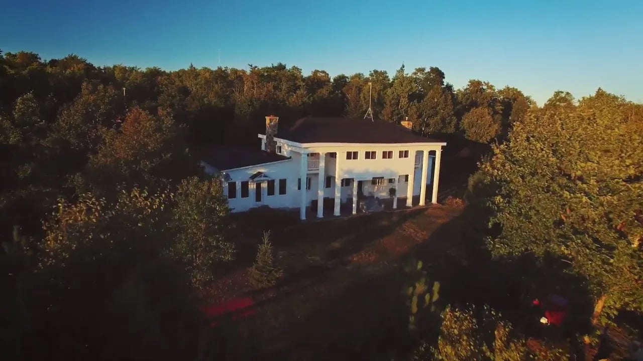 Aerial view of the white main lodge surrounded by autumn trees at sunset