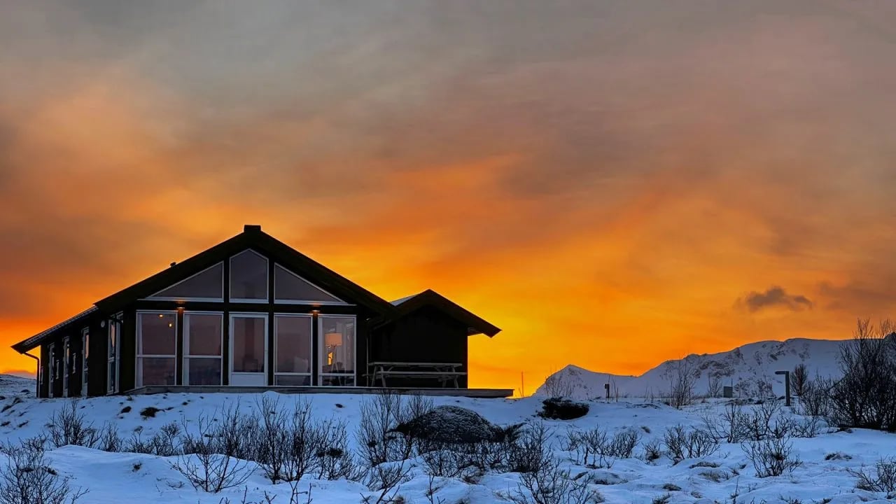 Lodge building in a snowy landscape under an orange sunset sky