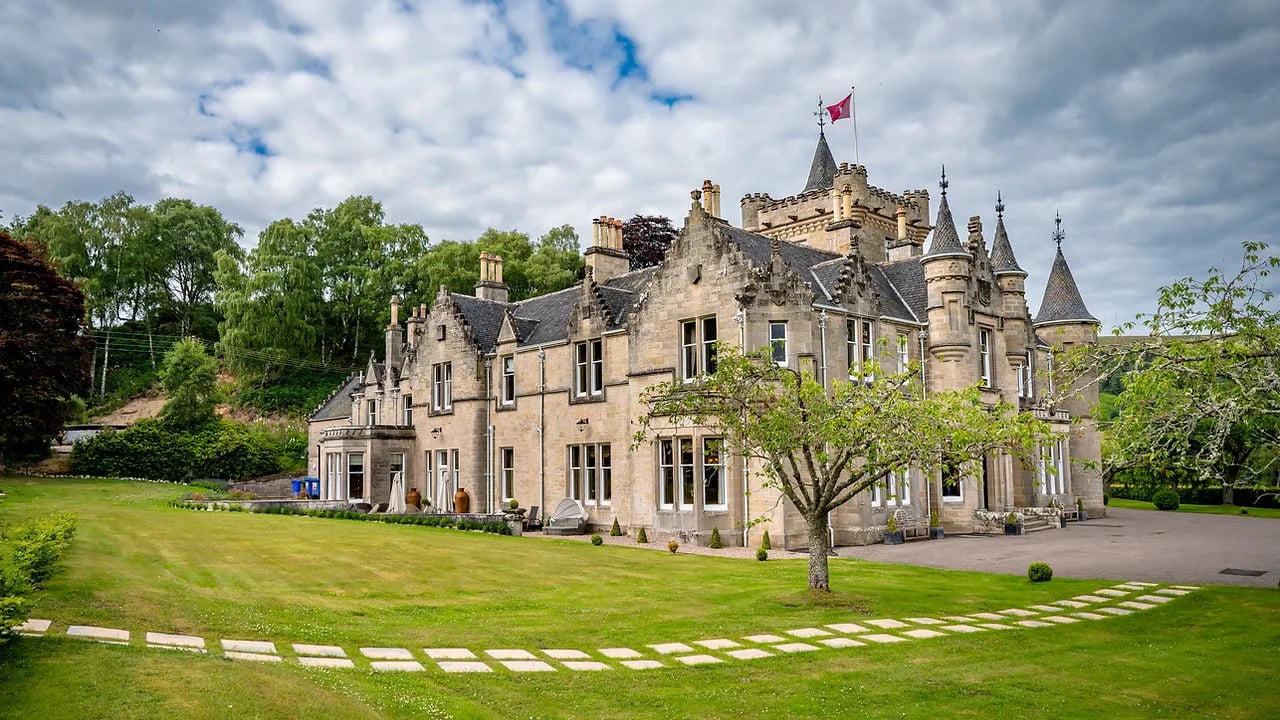 Rothes Glen castle with its turrets and flag flying under a partly cloudy sky.