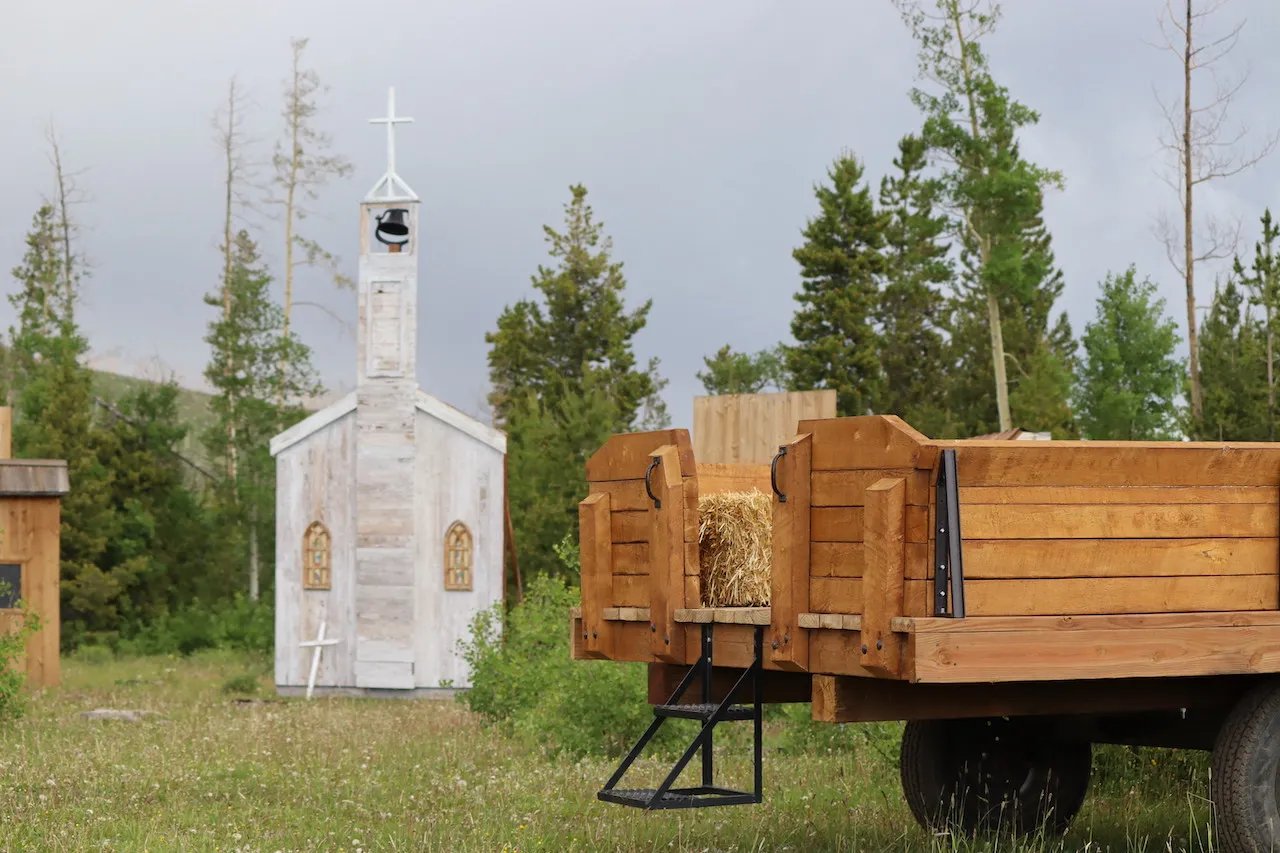 Hay wagon with a small white chapel in the background on a grassy field