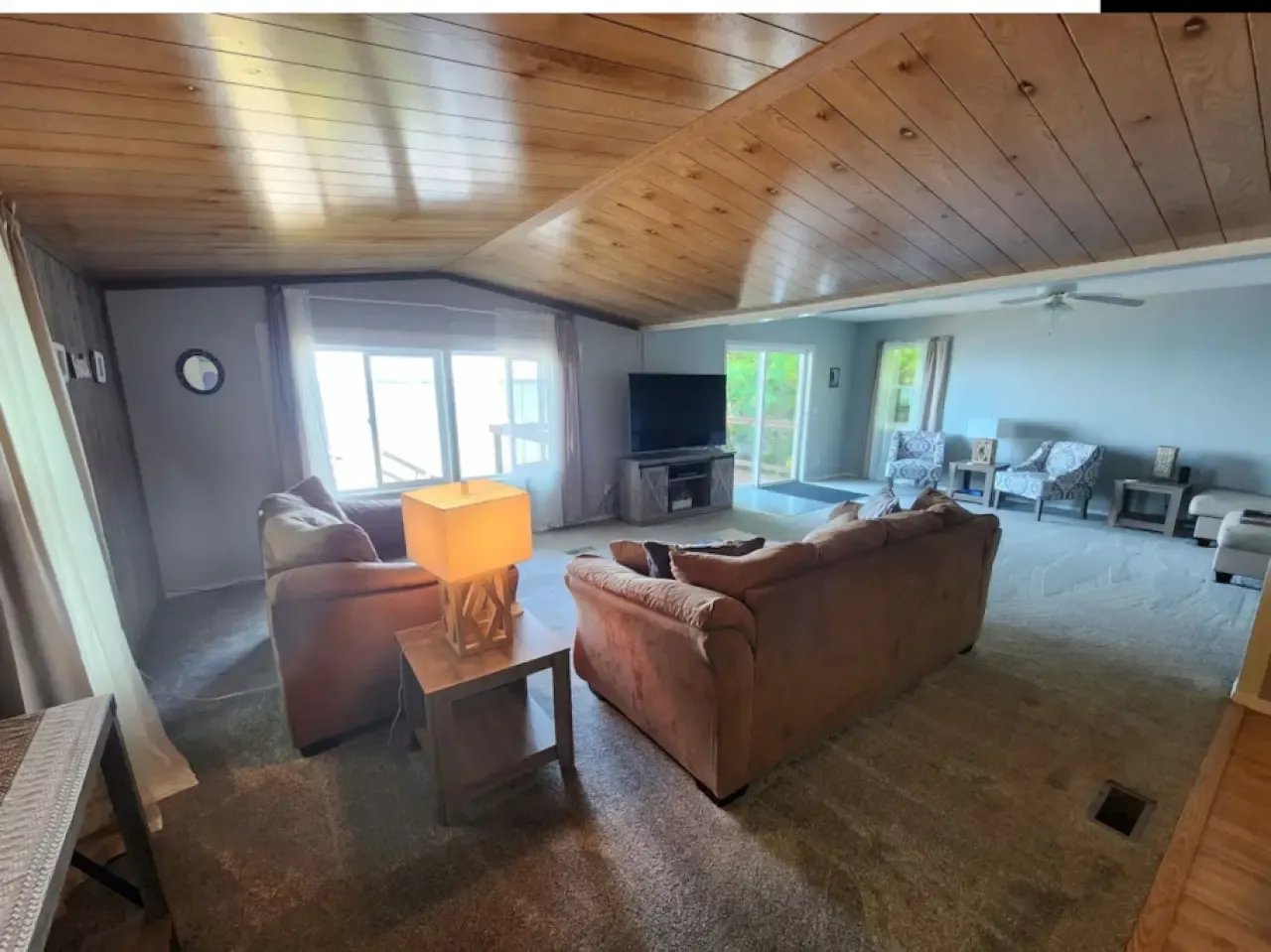 Spacious living room with wood-paneled ceiling and two comfortable sofas