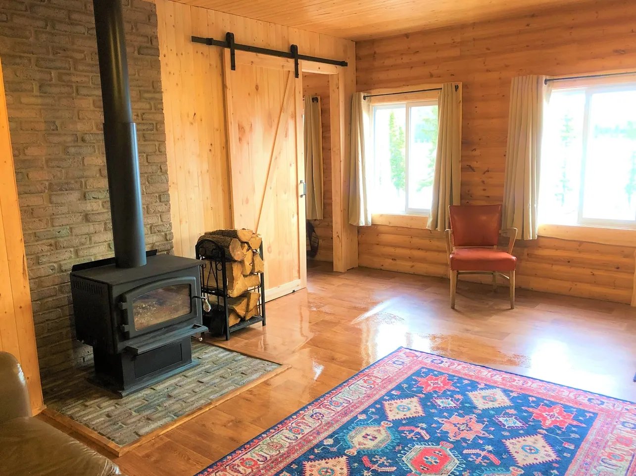 Living room with a black wood stove, barn door, and a colorful rug