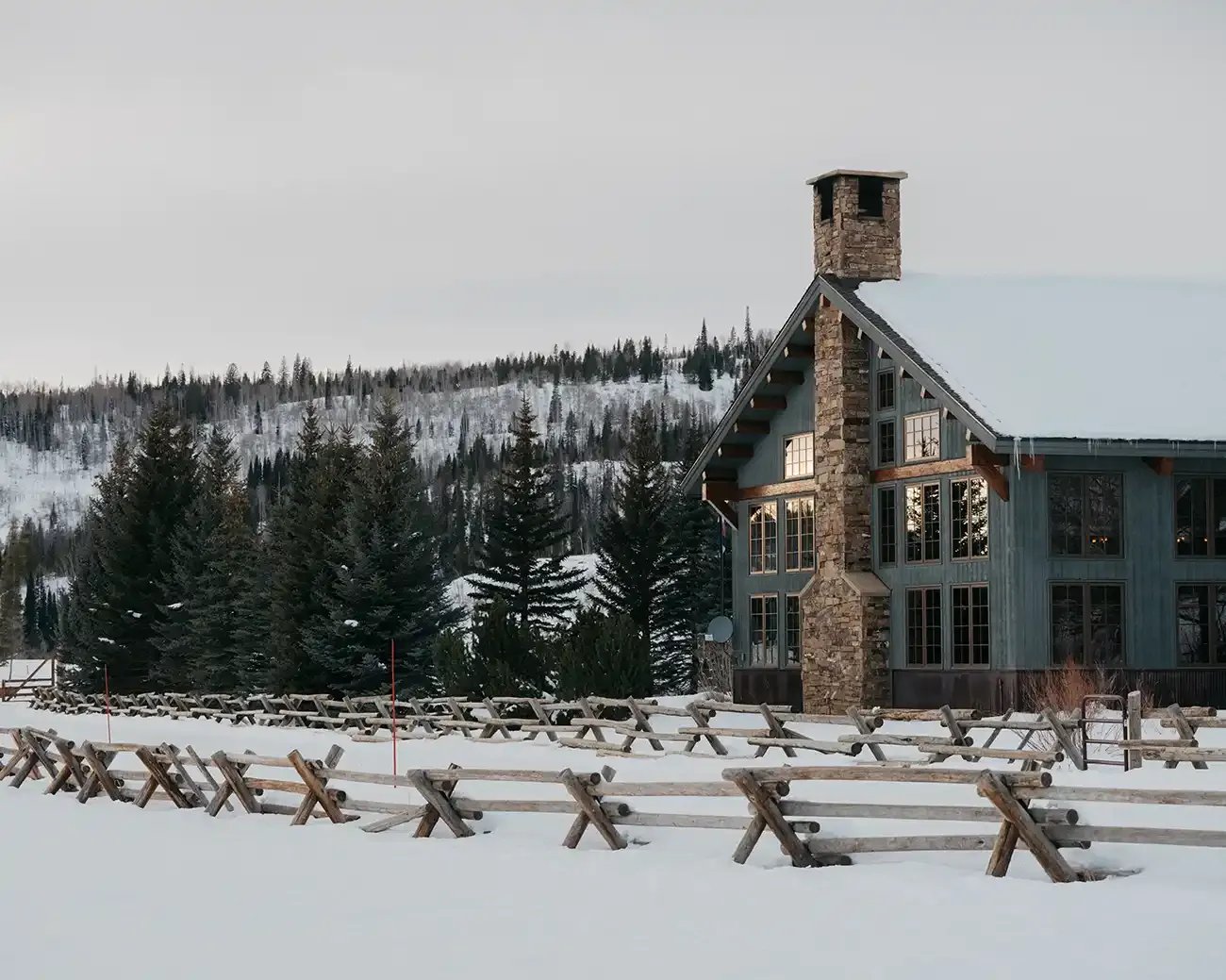 Large stone and timber lodge building in a snowy landscape with pine trees