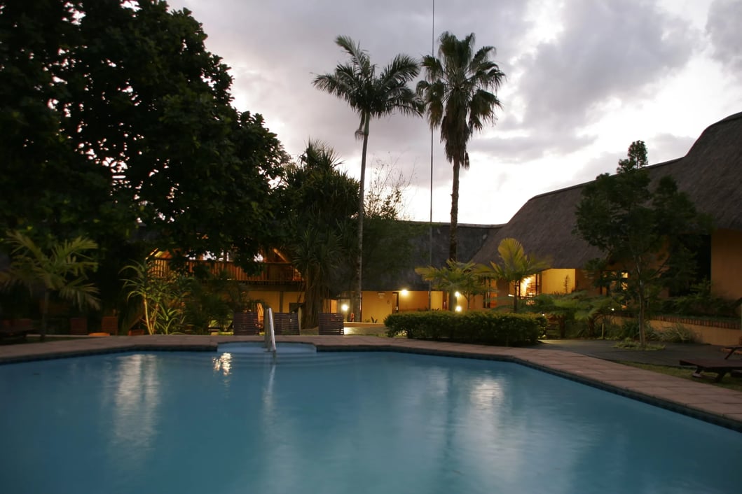 Modern lodge entrance with a high-pitched thatched roof, lit at night