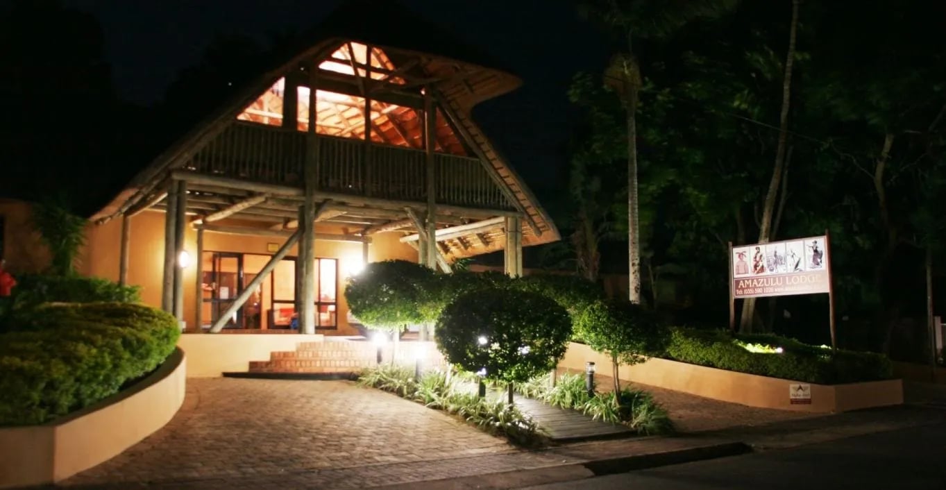 Lodge exterior with a swimming pool and lush tropical gardens at dusk
