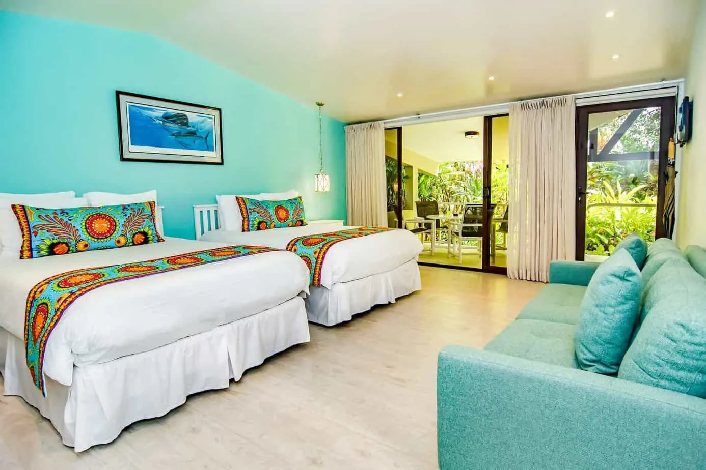 Classic room with two queen beds, a turquoise sofa, and sliding doors to a patio