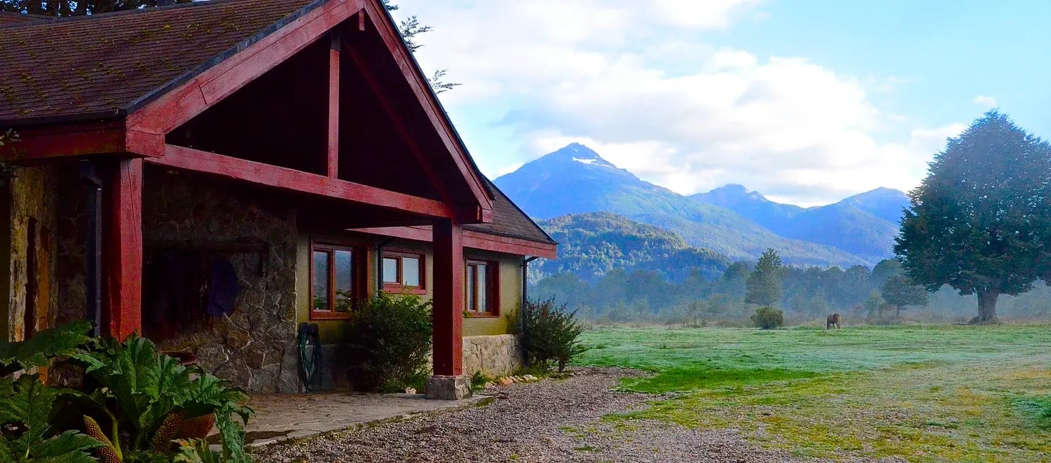Lodge entrance with a red roof and distant mountains