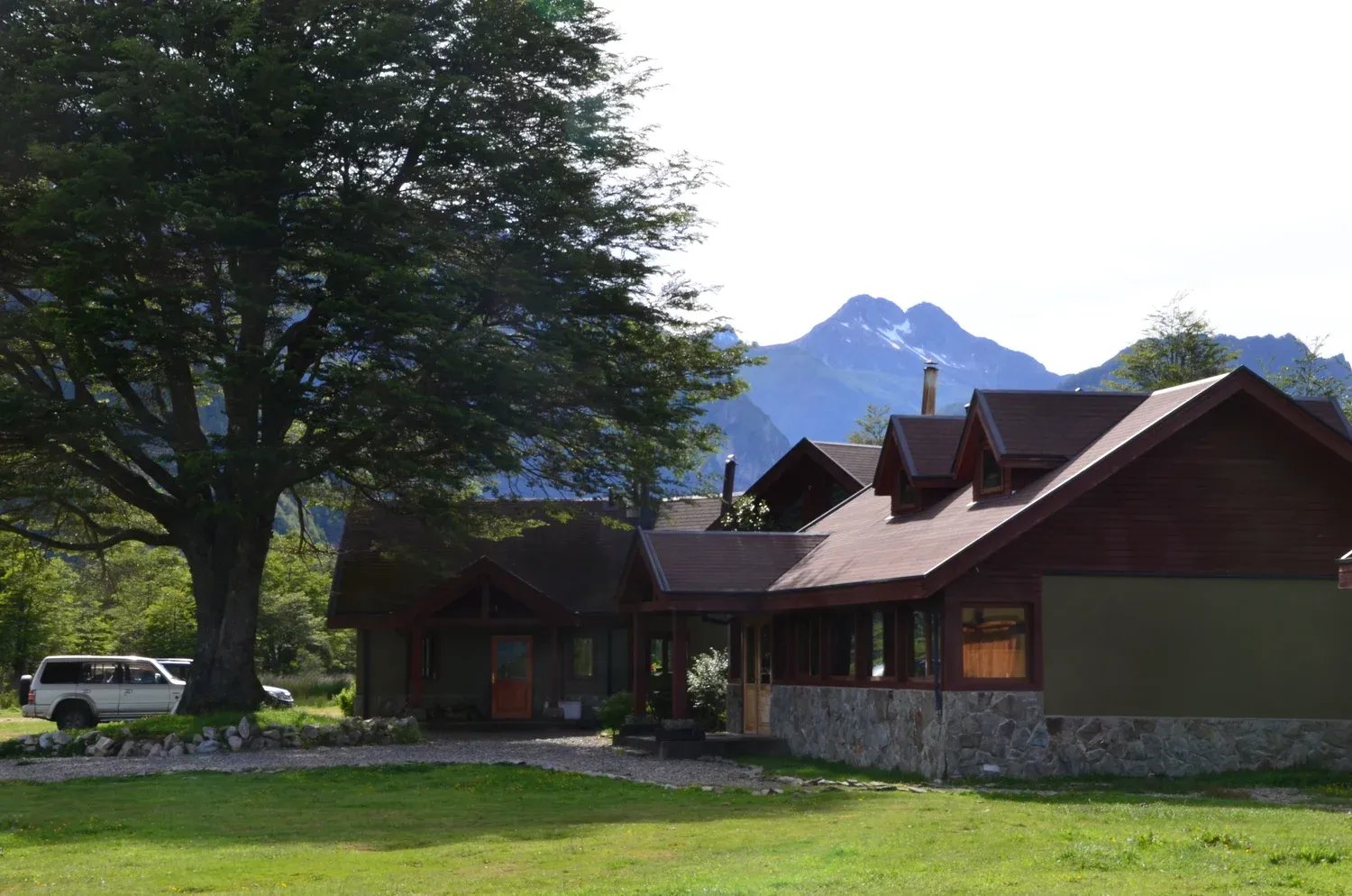 Lodge building with a large tree and mountains in the background