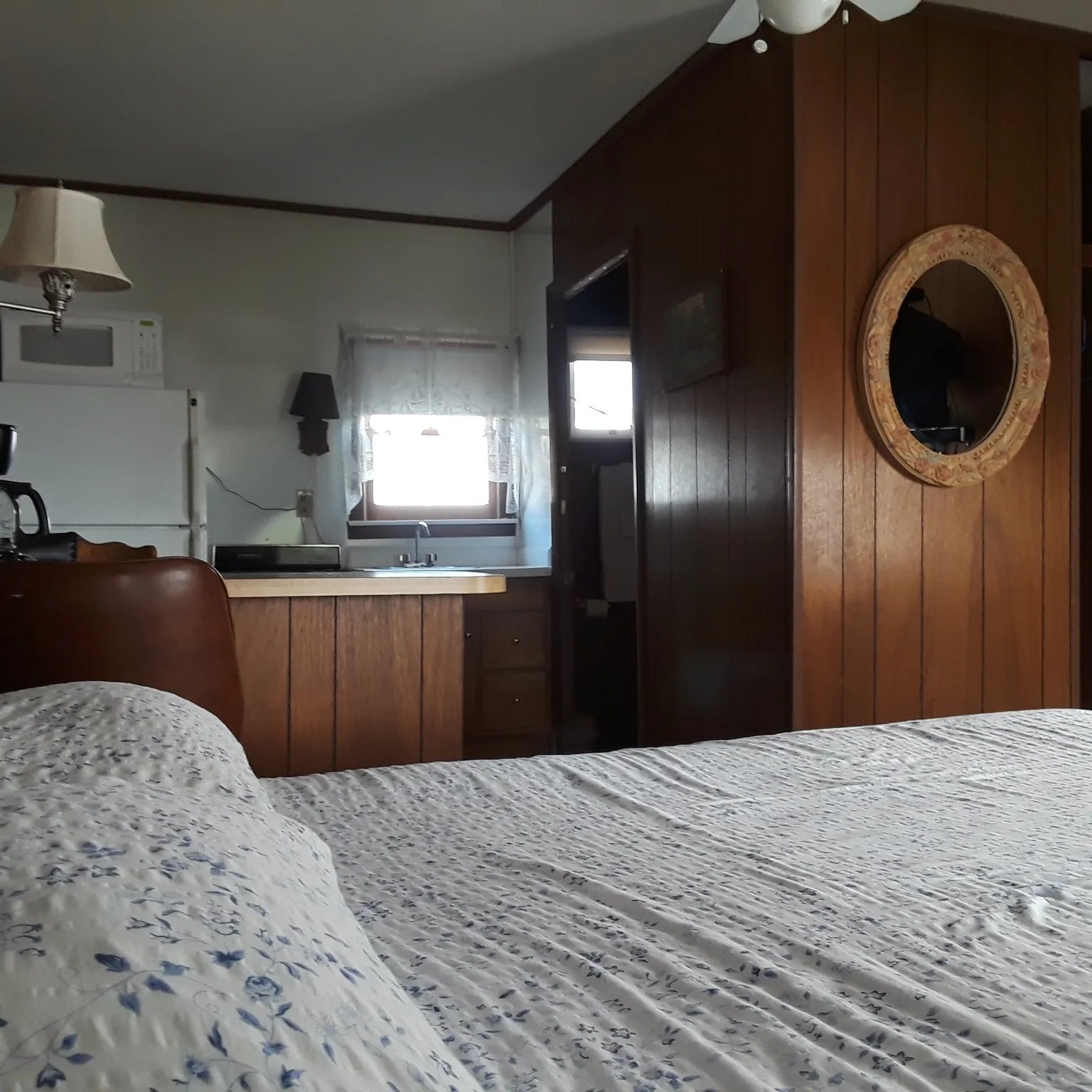 Cabin 7 bedroom with a patterned bedspread and a view into the kitchenette