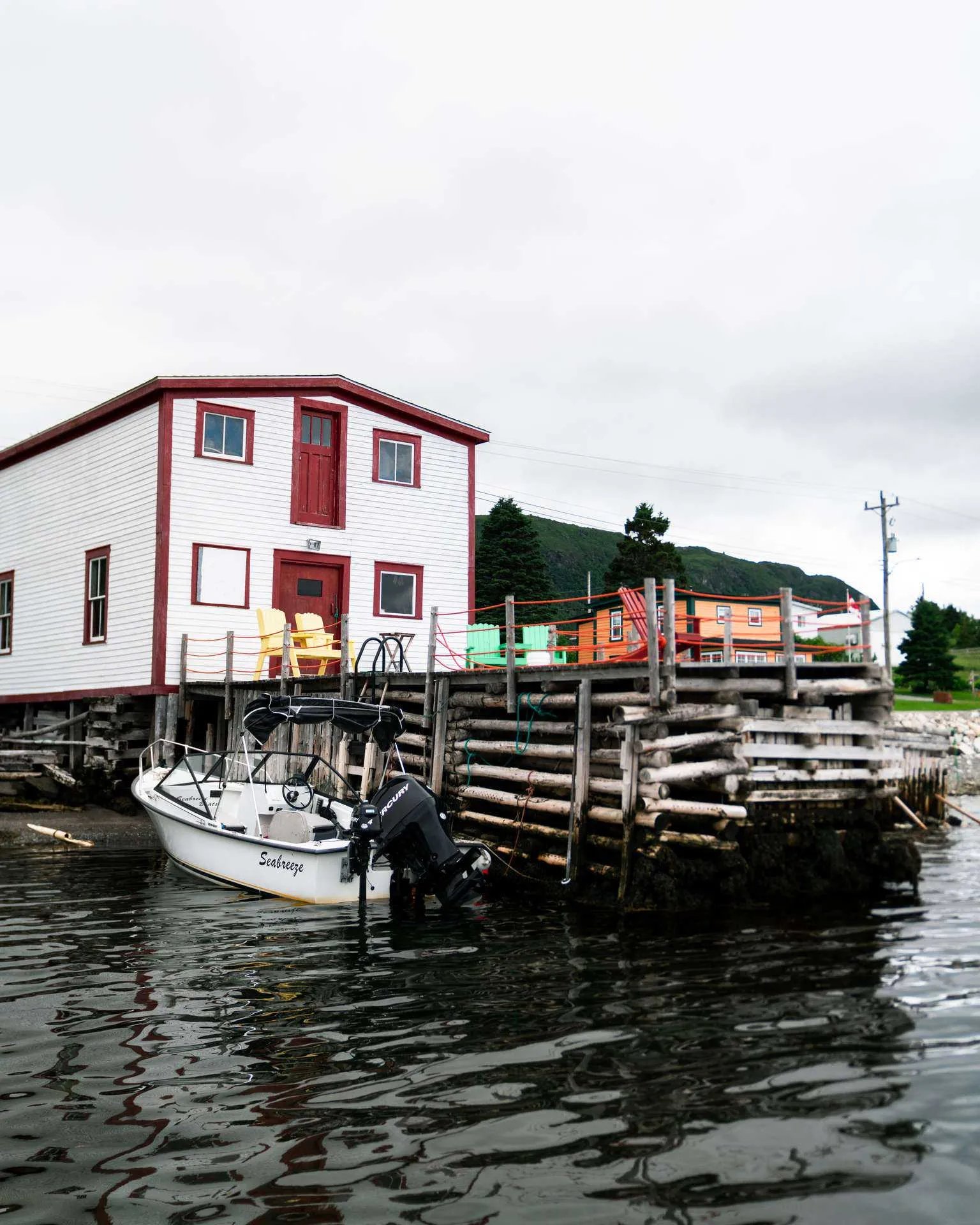 White and red building on stilts with a small boat at a wooden dock