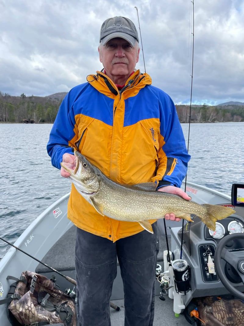 Man in blue shirt holding a Brook Trout in a river.
